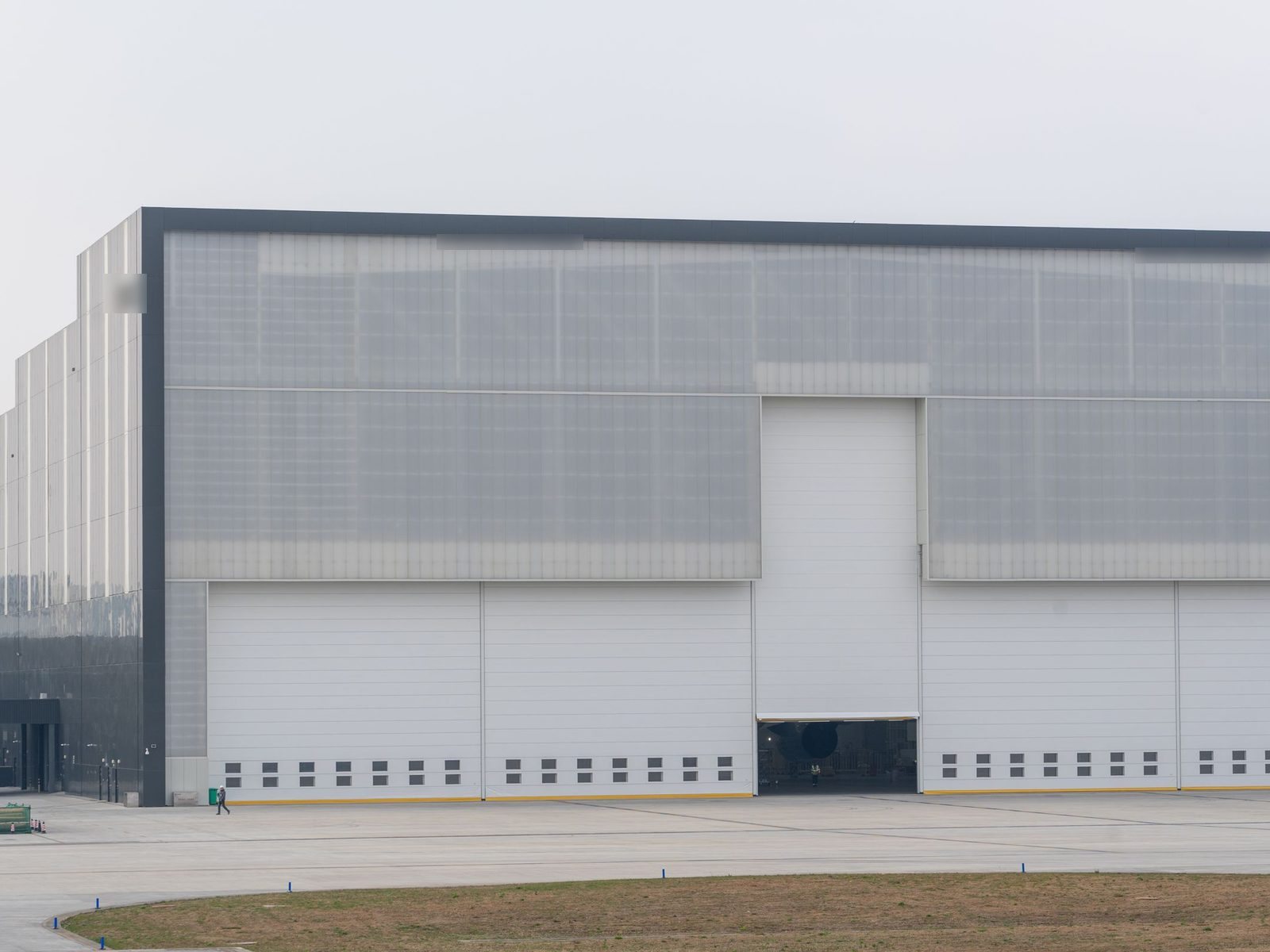 Large gray industrial building with white sliding doors